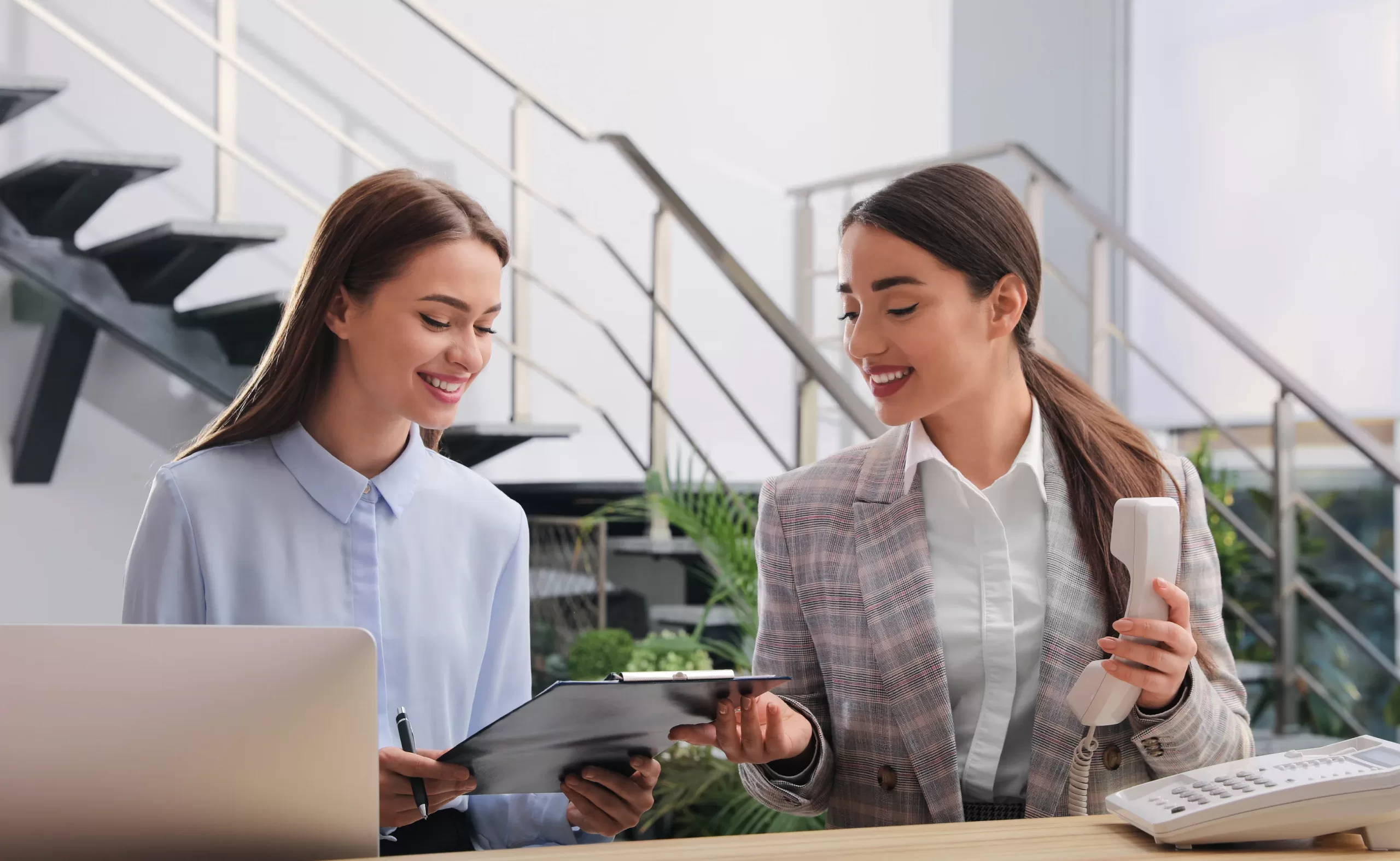 Two staffed hotel receptionists working the hotel lobby.