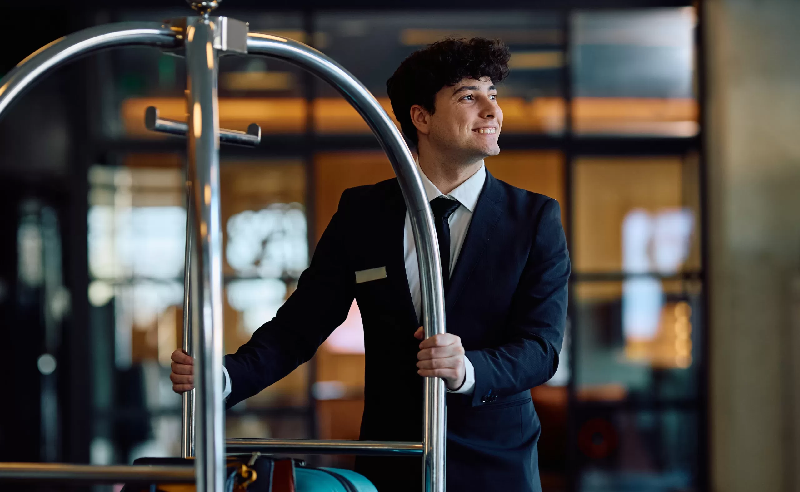 Bellman smiling while working hard in the reception of a luxury hotel.