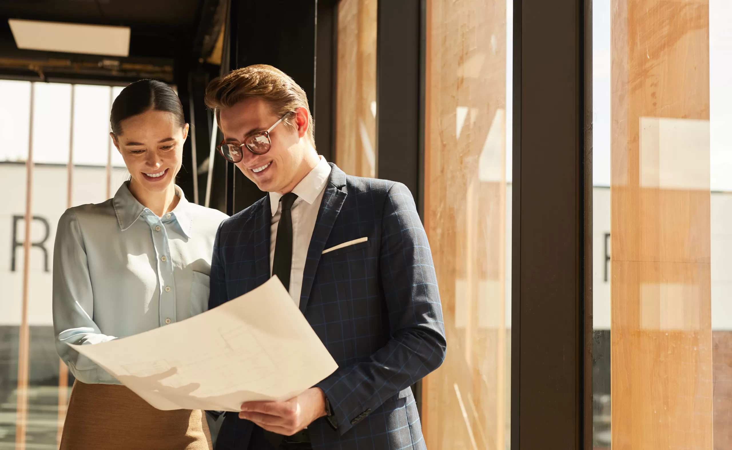 a female and male facility manager stand in the lobby or new floor of a hotel looking over the floor plans of the building