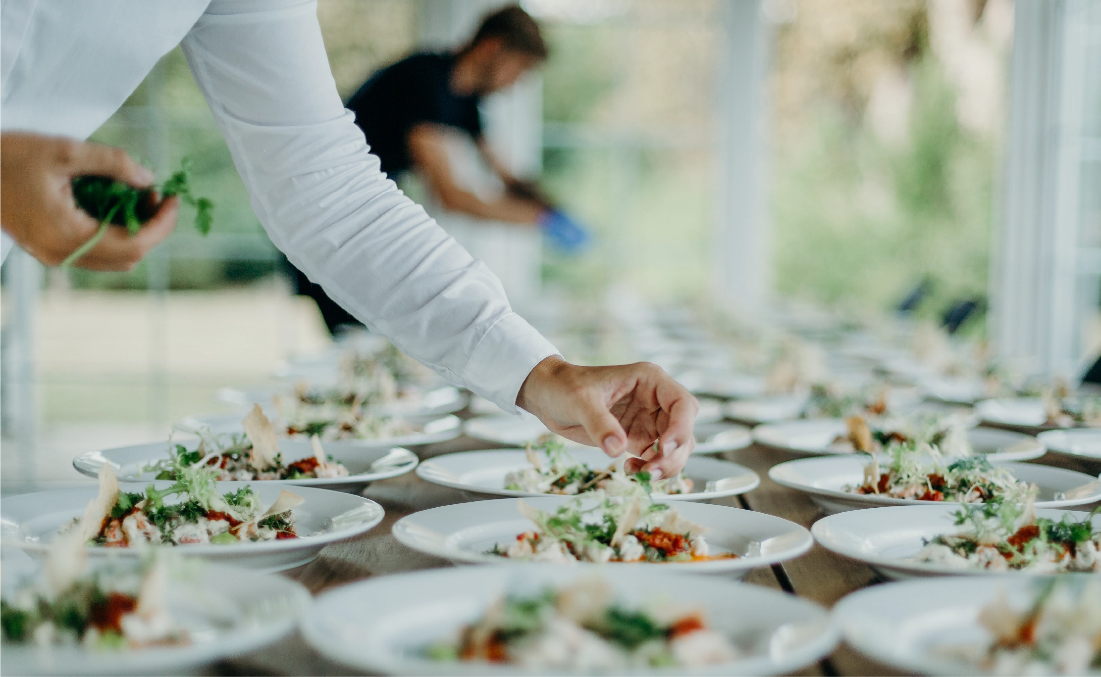 Hospitality server garnishing a plate at a corporate or wedding celebration