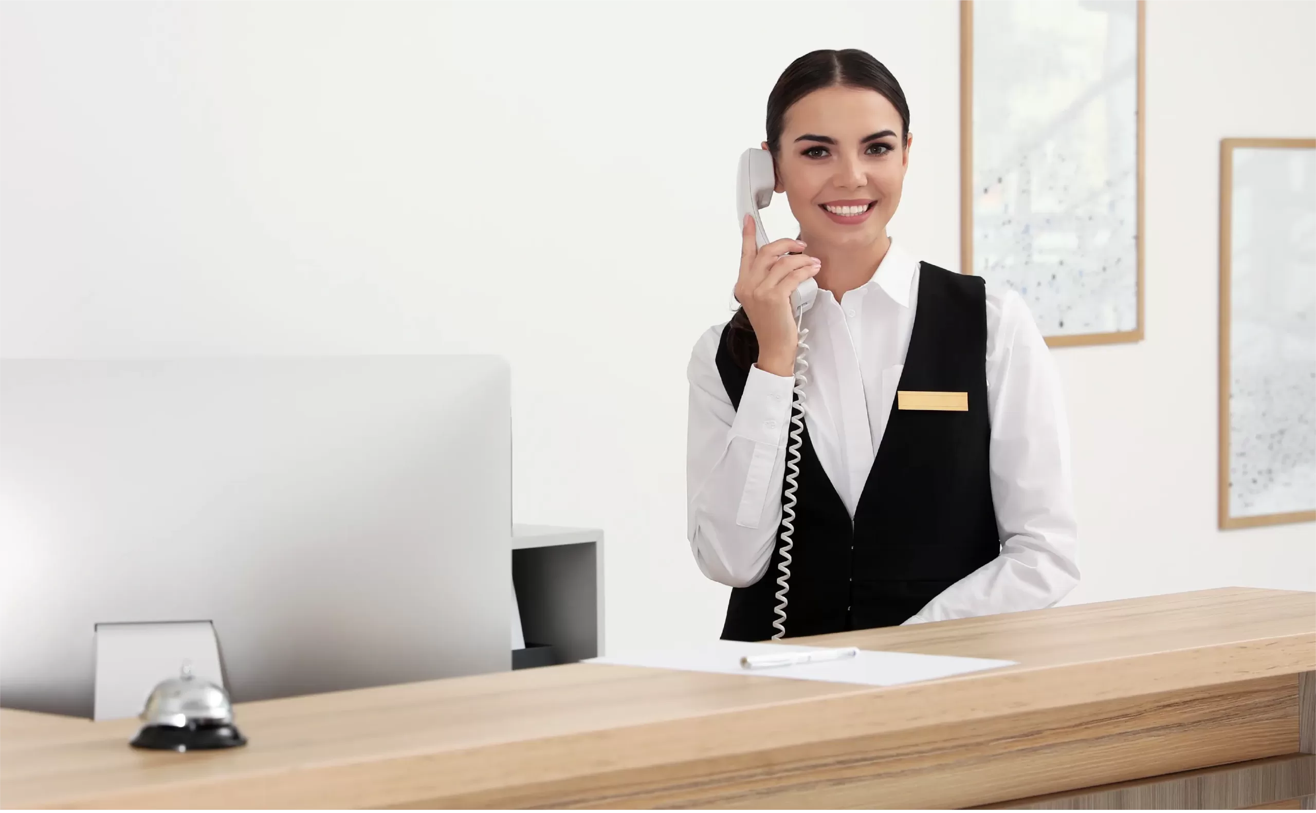 Woman in the hospitality industry answering front desk phone.