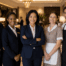 Hotel management representative standing with housekeeping, maintenance, front desk, and food service staff in an upscale hotel lobby.